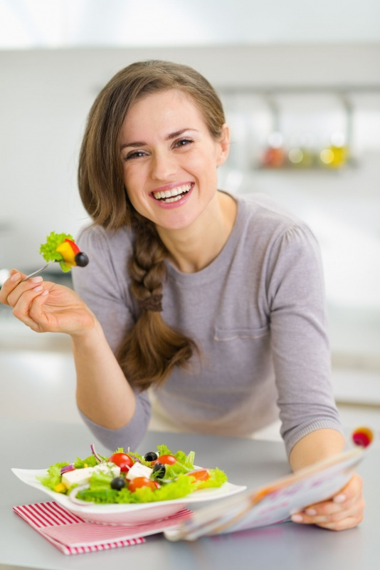 bella donna sorridente con forchetta in mano piatto insalata pomodori lattuga